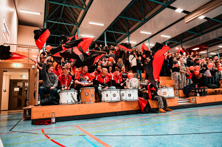 Bei den Heimspielen des MTV Braunschweig in der Sporthalle Alte Waage ist Block A fest in der Hand des leidenschaftlichen Fanklubs Harzblock 383 aus Schladen. Foto: Lando Reinberger